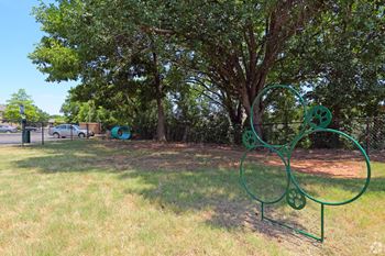 A green metal sculpture of a dog is in a grassy area.